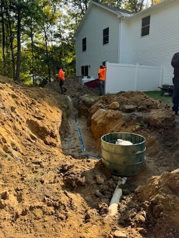 A man is standing in the dirt next to a house.