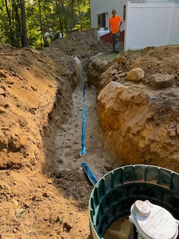 A man is standing in a trench next to a septic tank.