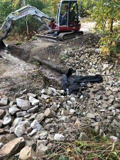 A small excavator is digging a hole in a pile of rocks.