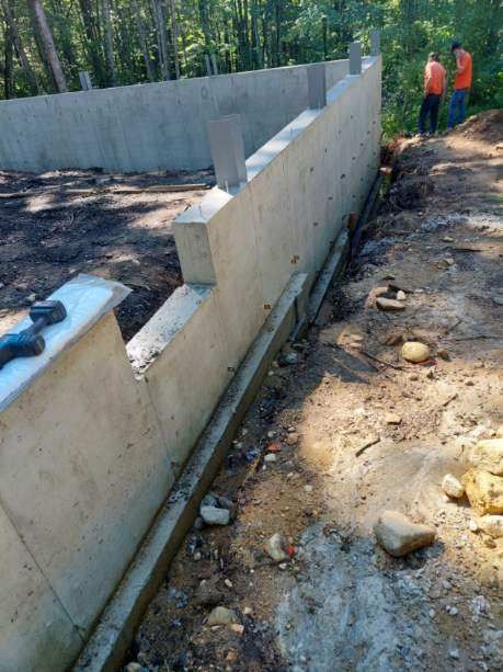 A concrete wall is being built in the middle of a dirt field.