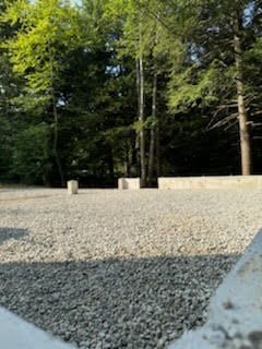 A gravel area with trees in the background.