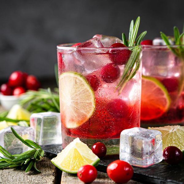 A close up of a drink with ice cubes and berries on a table.