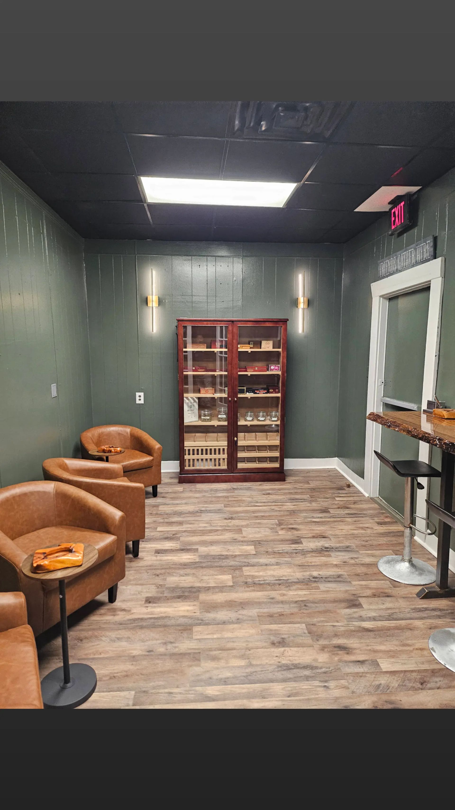 A room with chairs , a table , and a cabinet filled with cigars.