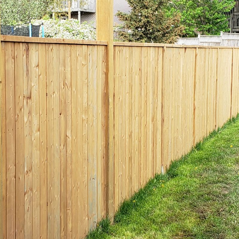 A wooden fence surrounds a lush green yard.