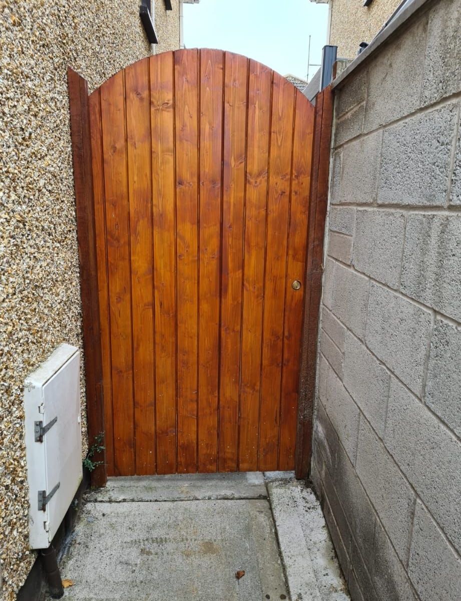 A wooden gate is next to a brick wall