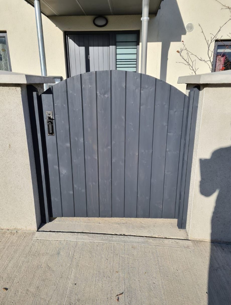 A gray wooden gate is in front of a house