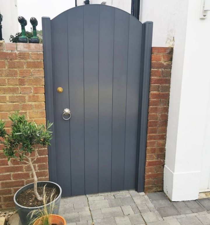 A black gate with a brick wall behind it