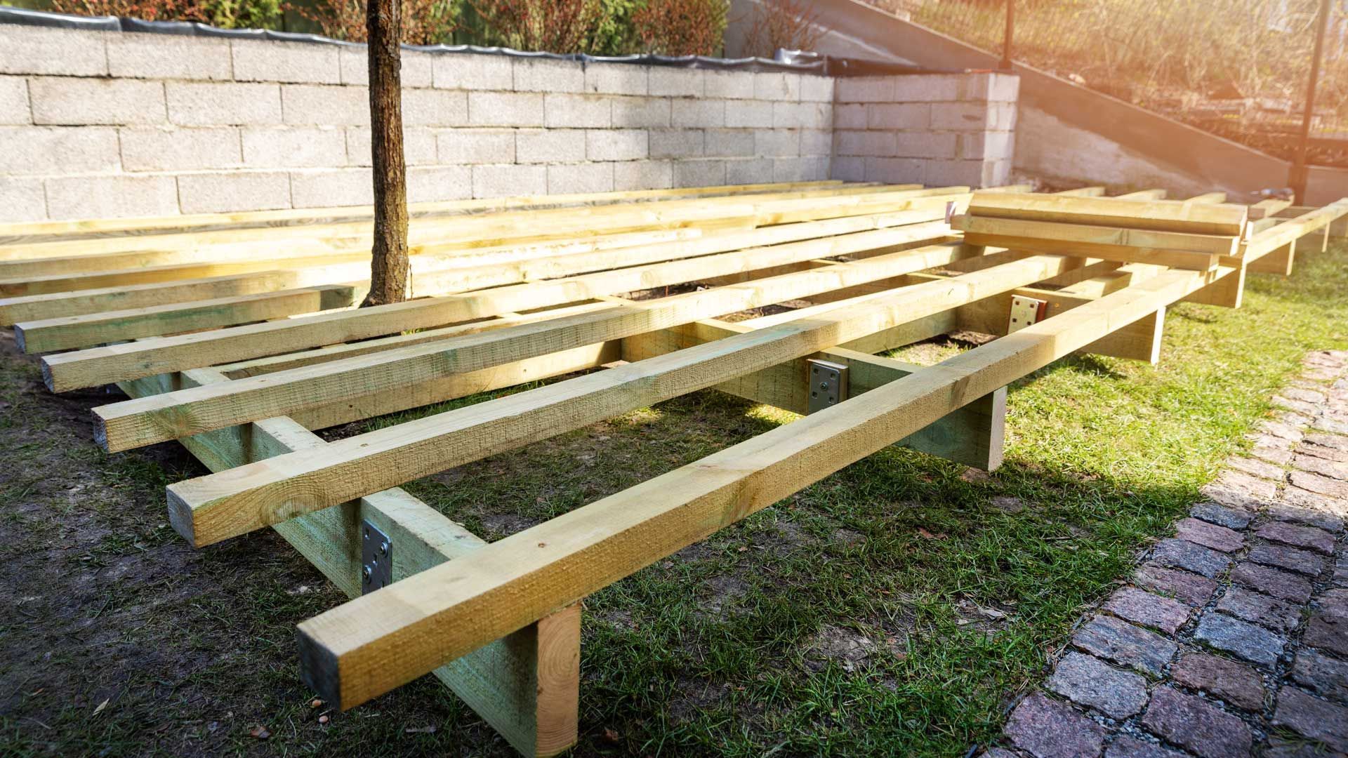 A wooden deck is being built in a backyard.