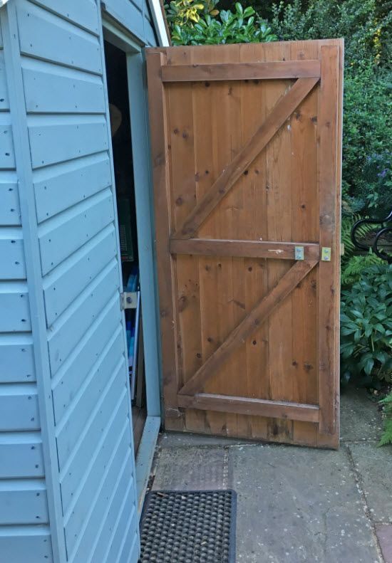 A wooden door is open on the side of a shed.