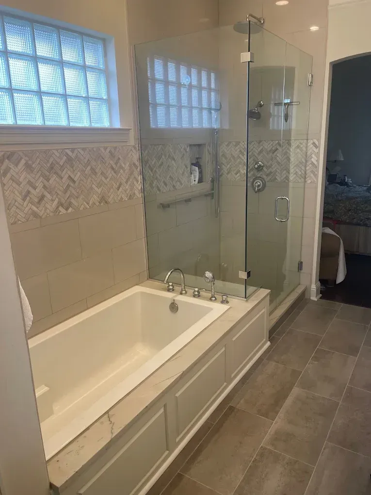 A bathroom with a tub and a shower with a glass door.