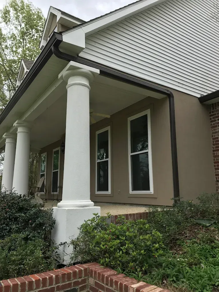 White pillars support a porch with brown trim and a tan exterior wall.