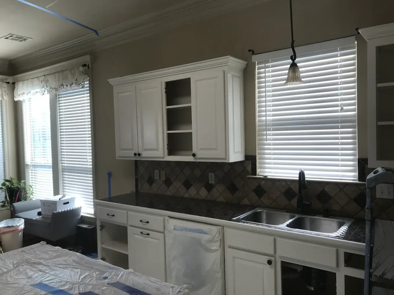 A kitchen with white cabinets and a stainless steel sink