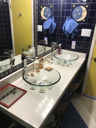 Bathroom with white countertop, glass sinks, blue tile, yellow door, moon decor.