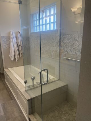 Bathroom with a glass shower door, bathtub, and decorative tile.