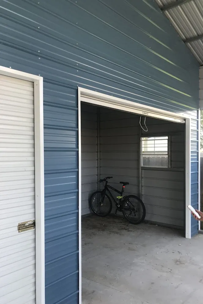 A woman is standing in a garage with a bicycle in it.