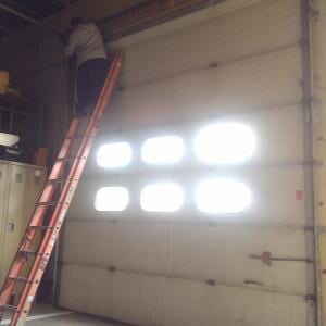 Man Fixing the Garage Door at the Top of the Ladder — Garage Doors in Baltimore, MD