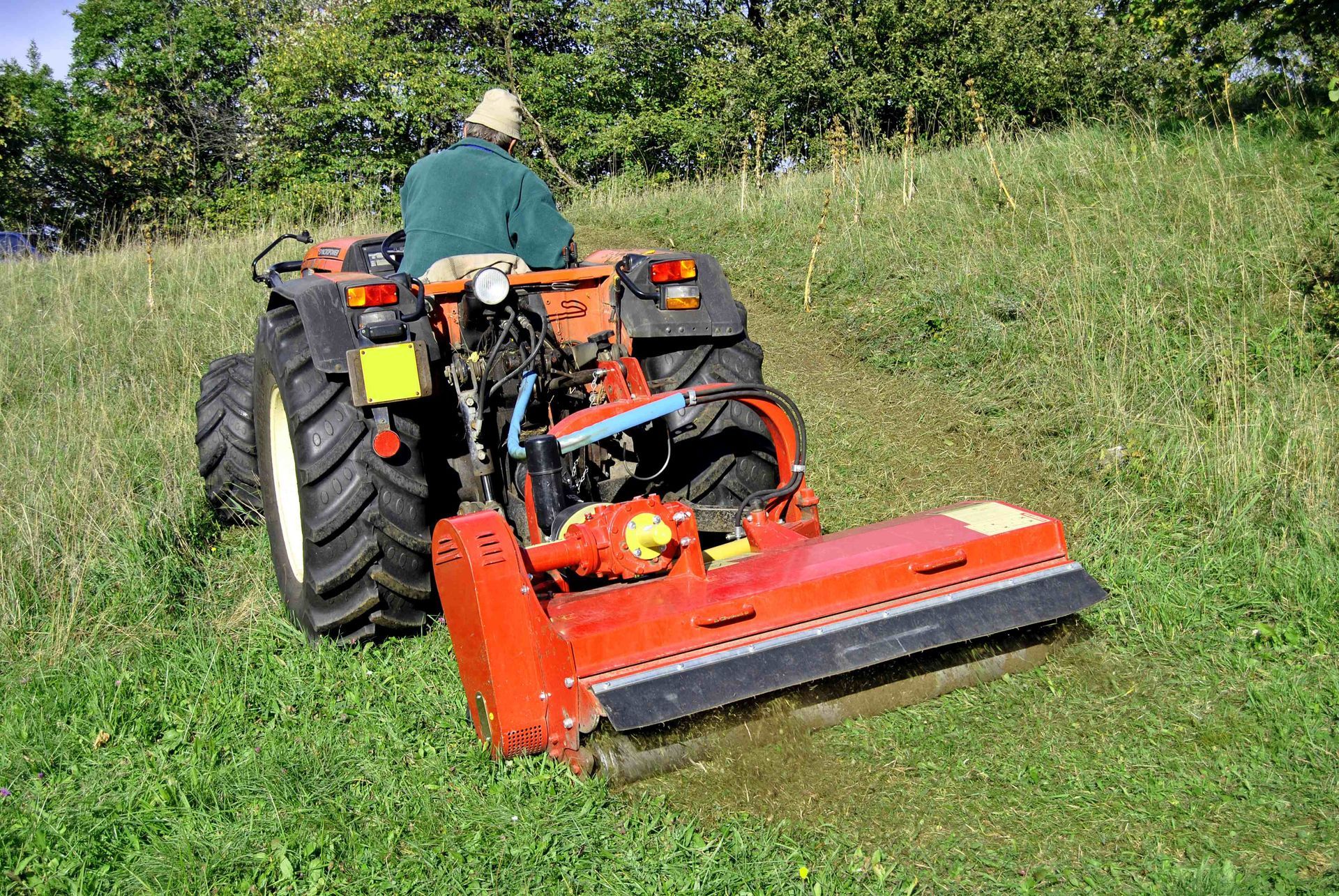 a man riding a tractor hogging the bush