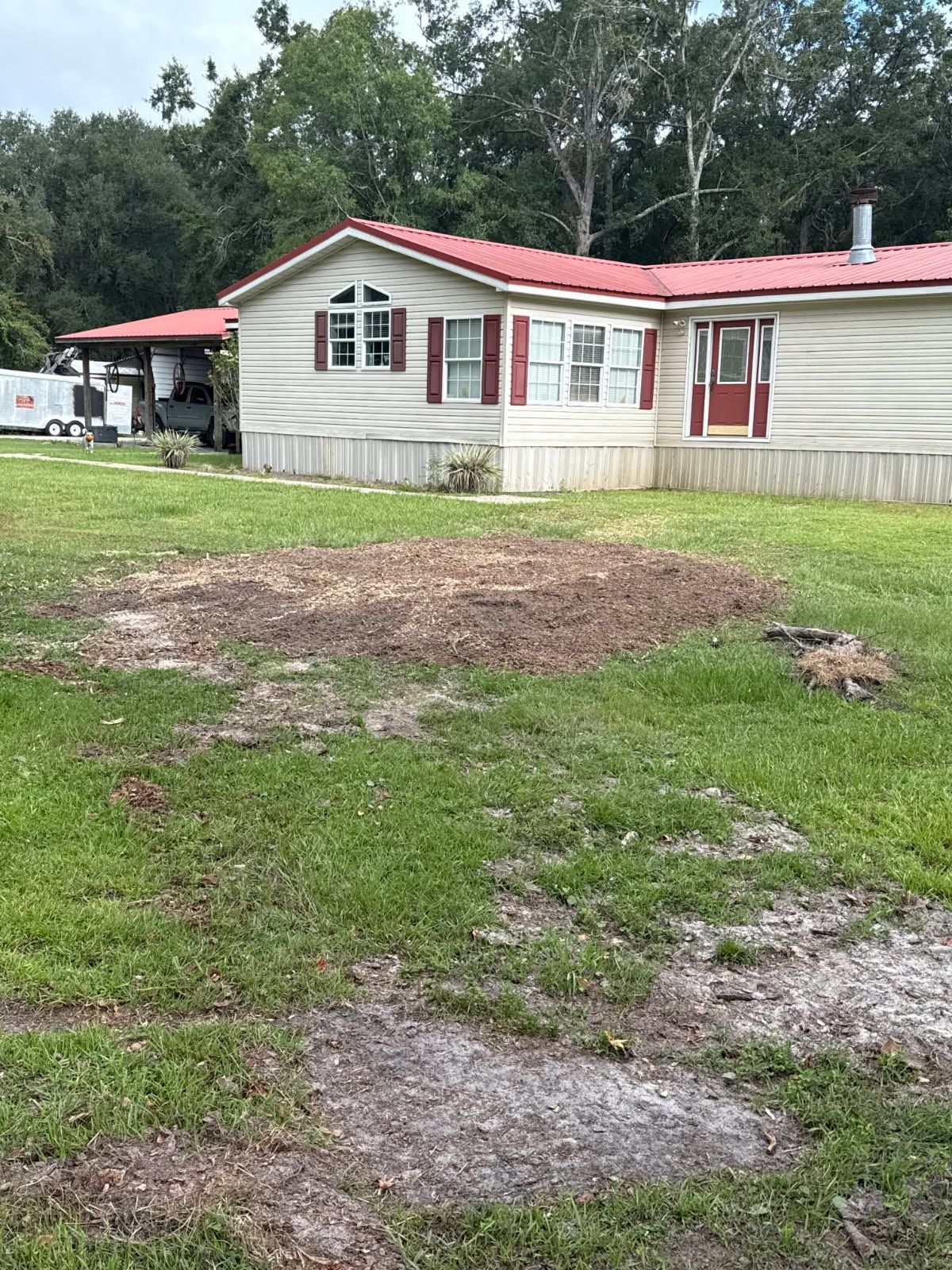 Mobile home with red roof and shutters, on a grassy lot.