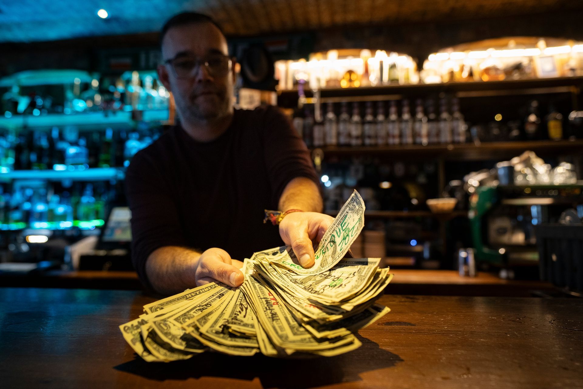 El dueño del pub Paddy de Rota muestra los billetes de dólar americano que sus clientes, en su mayoría estadounidenses, dejan en el establecimiento y con los que forra las paredes y el techo del local.