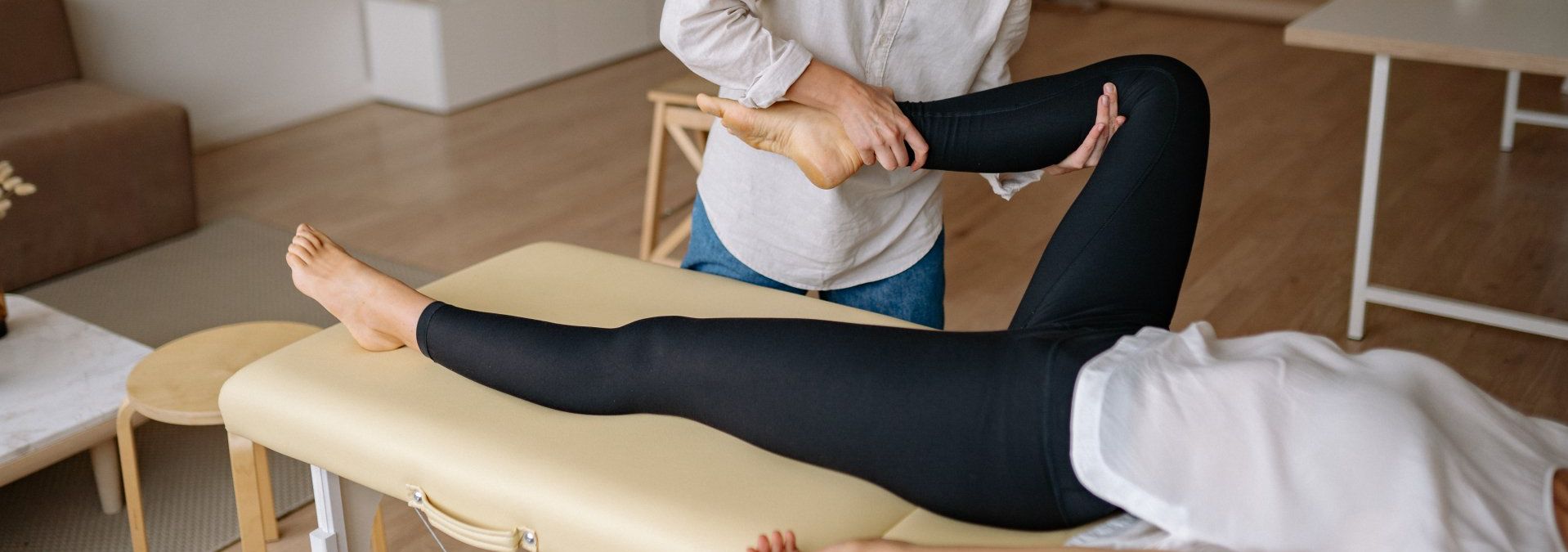 Un Kinésithérapeute étend la jambe d'une femme sur une table.