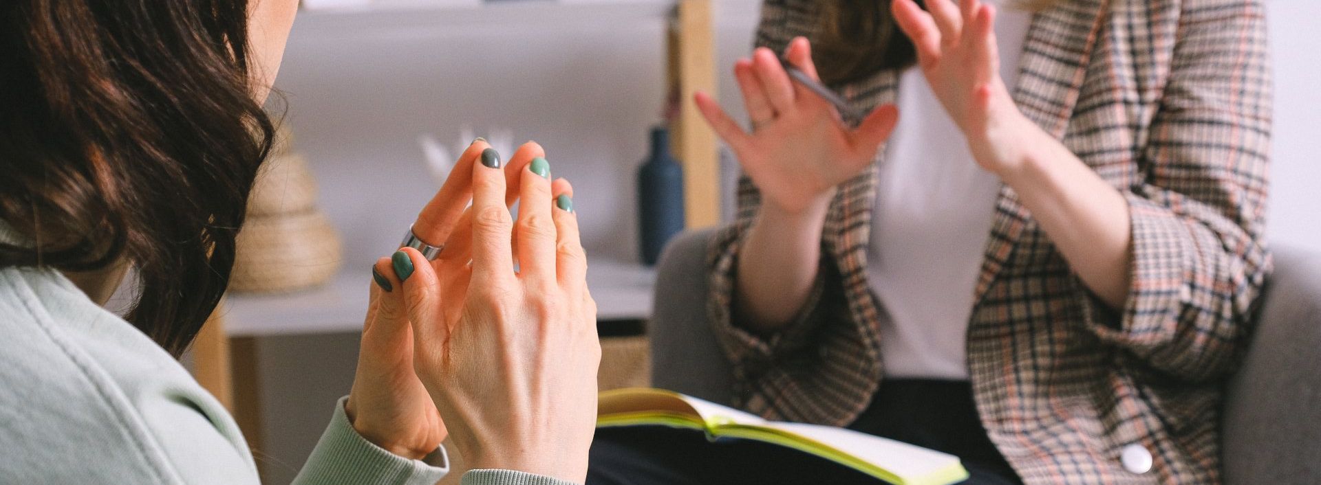 Une femme est assise sur un canapé, les mains jointes en prière.