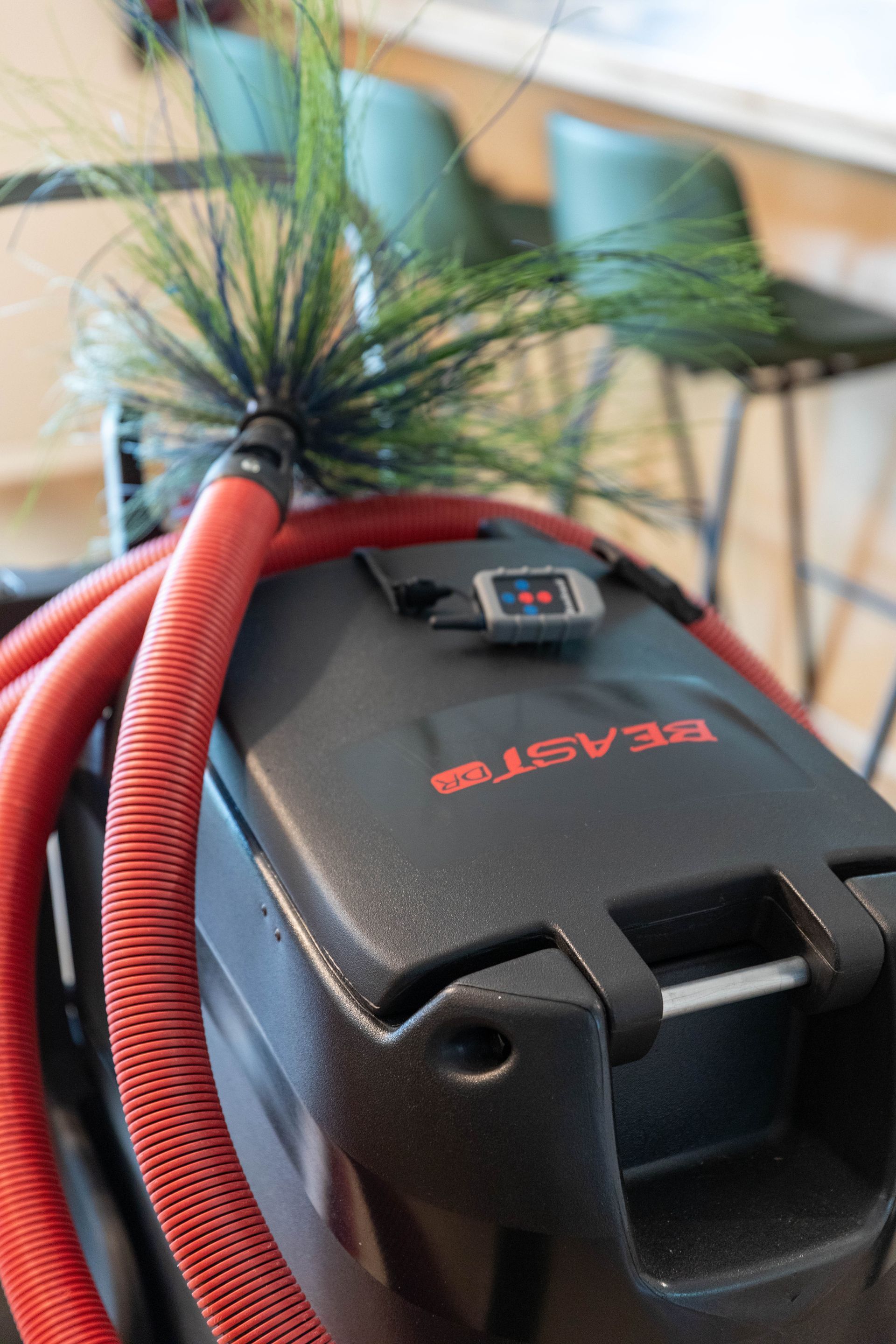 A technician in a blue shirt uses a caulk gun to apply sealant around a ceiling air vent.