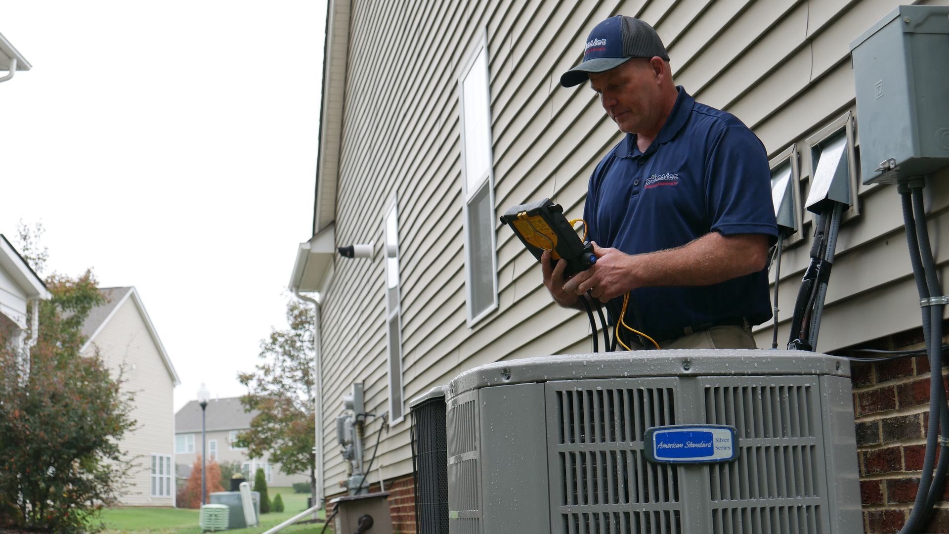 HVAC technician examining air conditioner unit outside a house.