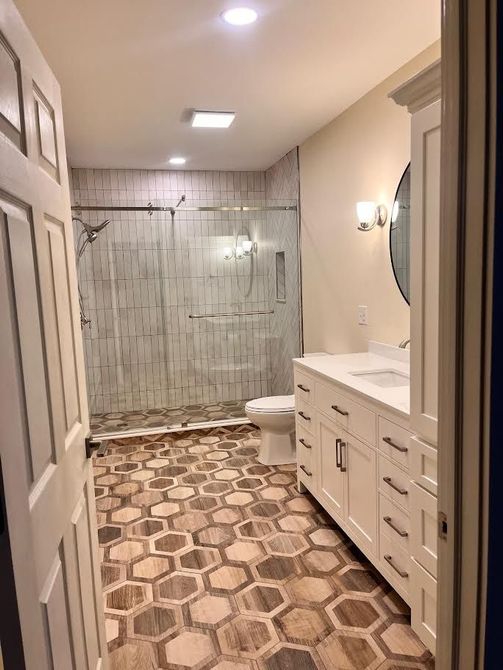 A bathroom with a walk in shower , sink , toilet and mirror.