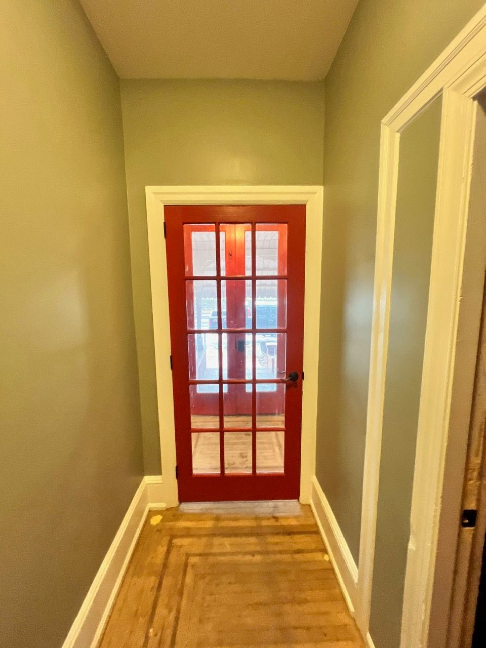 A hallway with a red door and gray walls