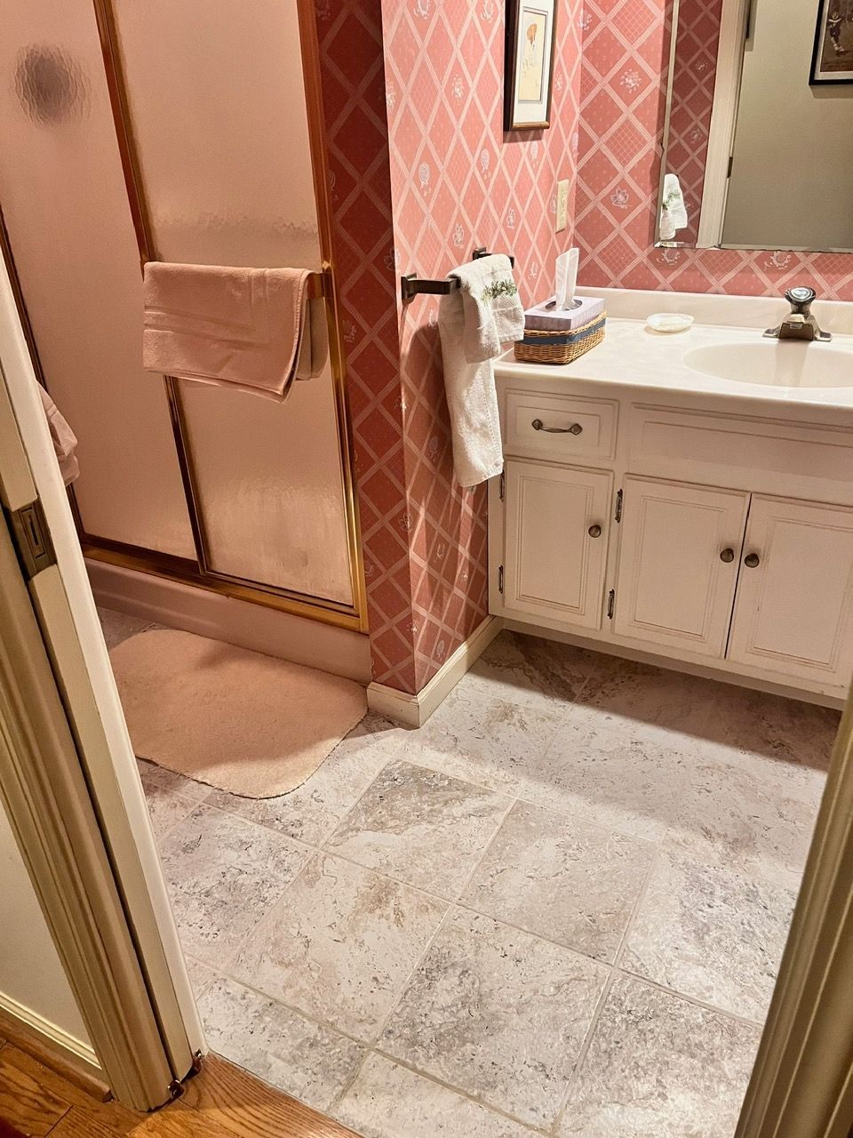 A bathroom with a sink , mirror , and shower stall.