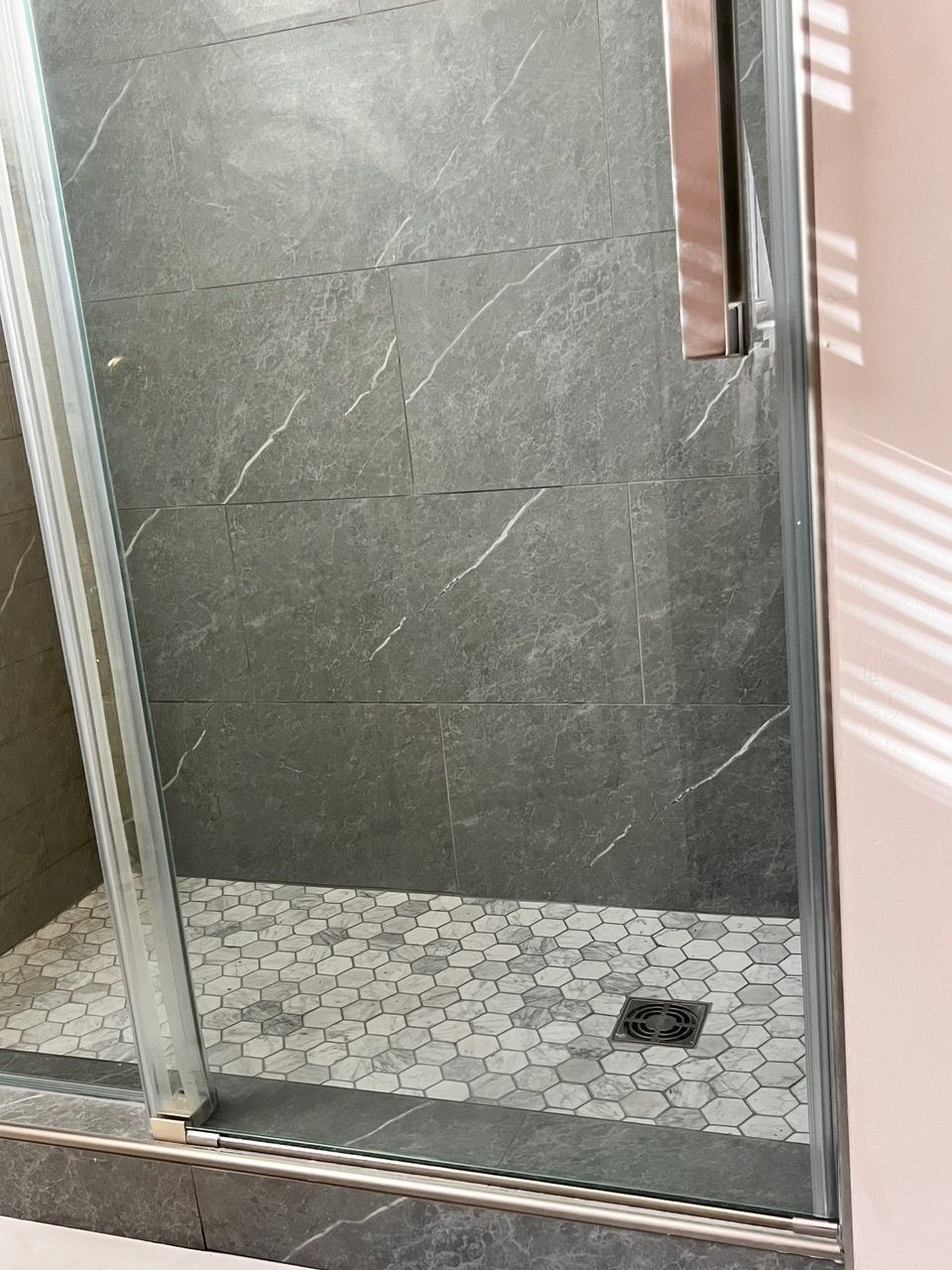 A shower stall with a glass door and a tiled floor