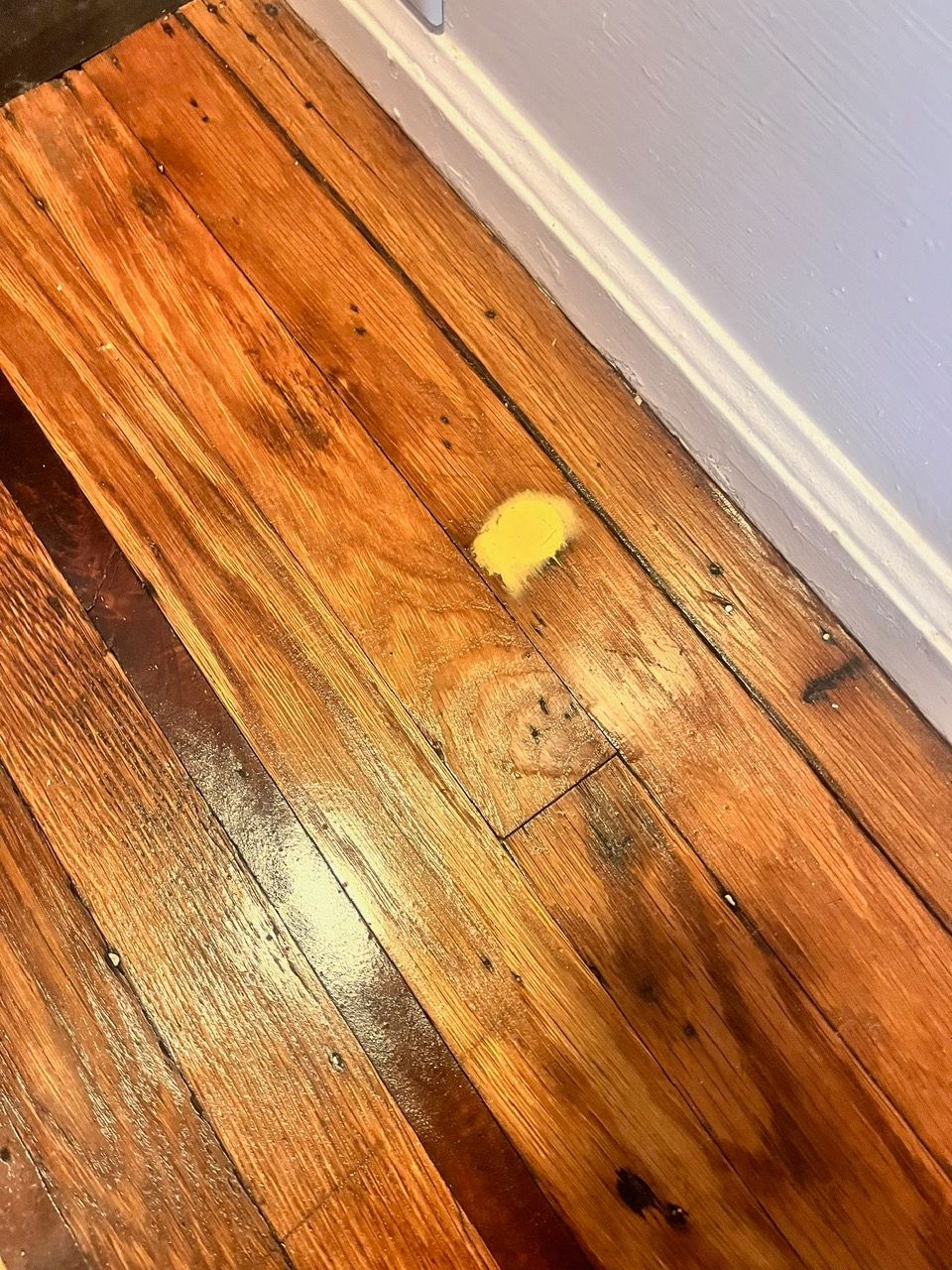 A piece of yellow paper is laying on a wooden floor.