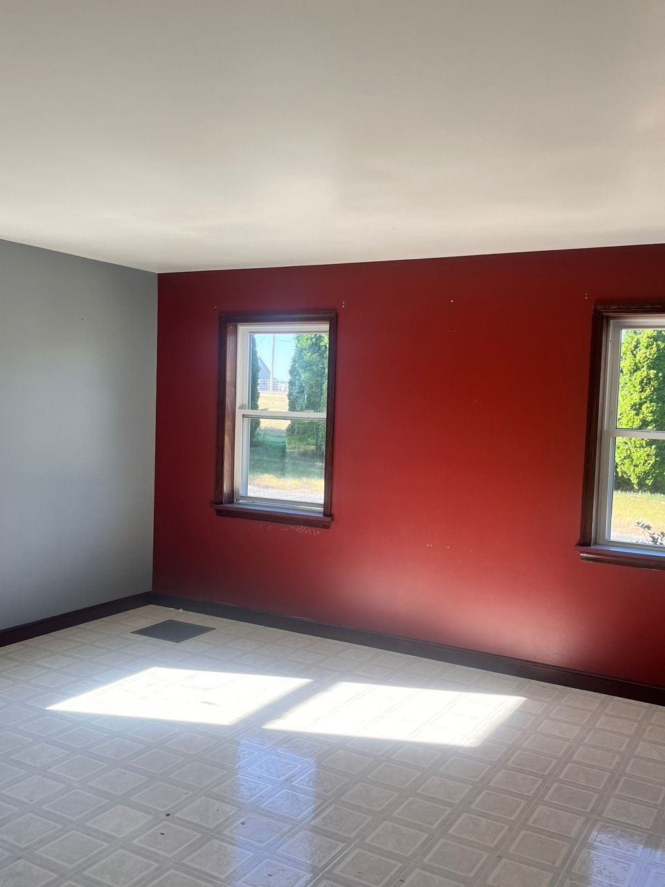 An empty room with red walls and two windows