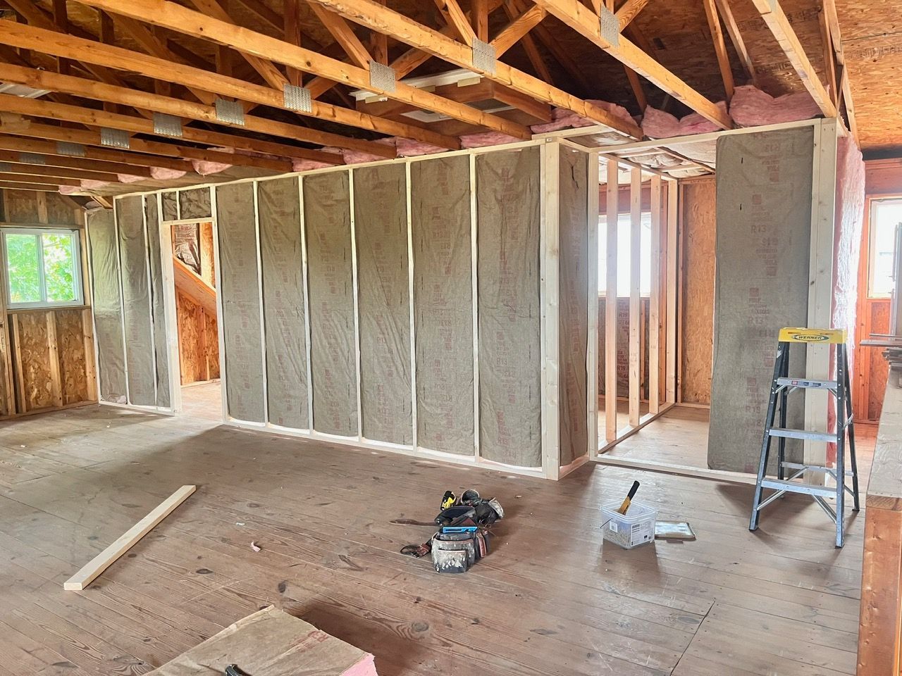 A room in a house under construction with a ladder and tools on the floor.