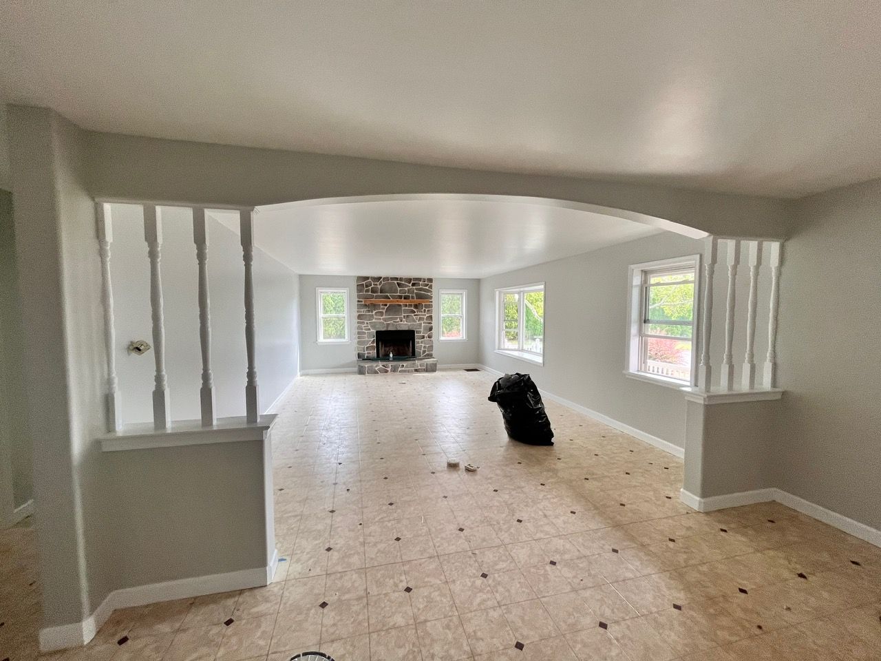 A large empty living room with a fireplace and windows.
