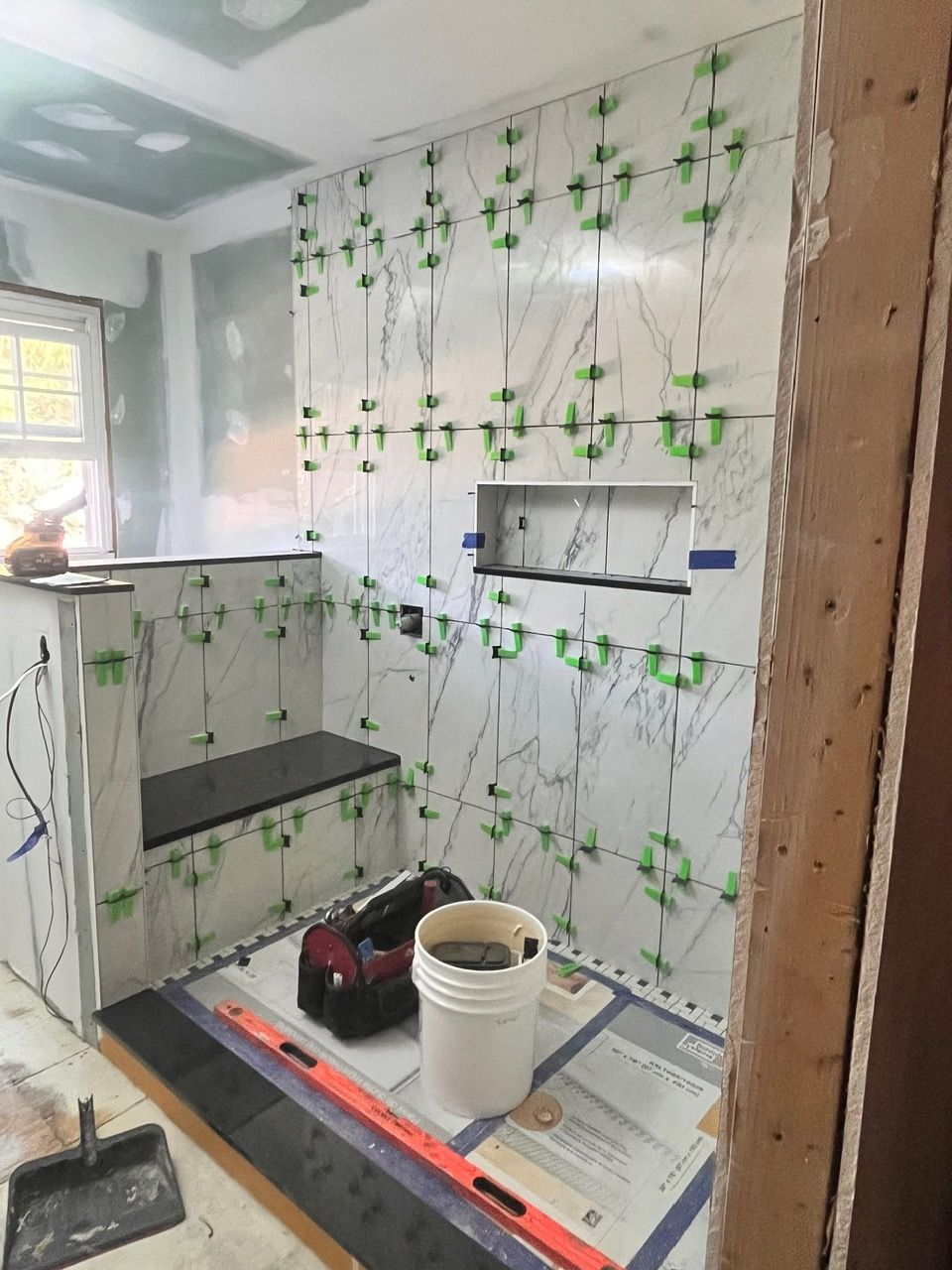 A bathroom under construction with a bucket and a level on the floor.