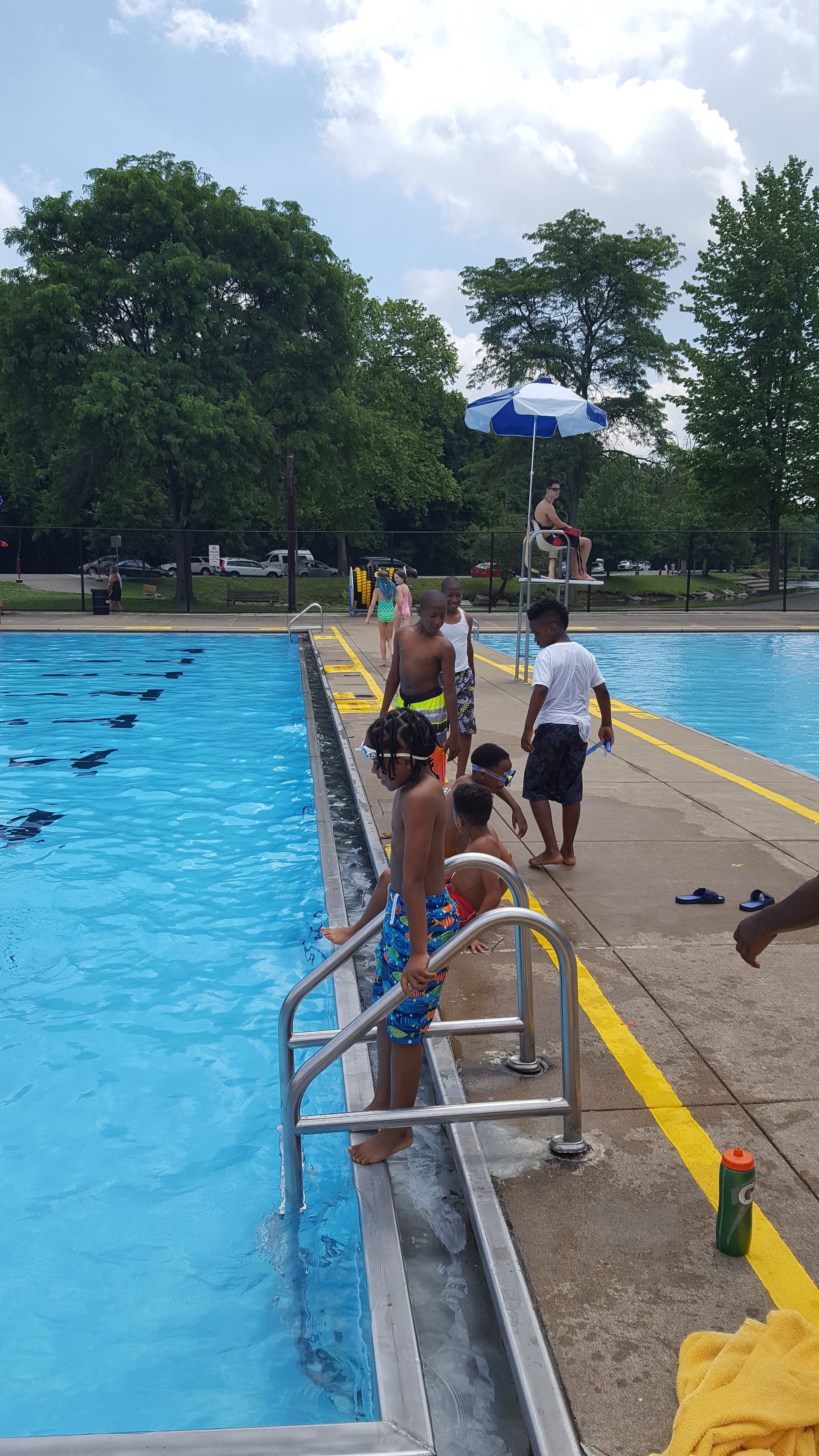 A group of children are standing on the edge of a swimming pool.