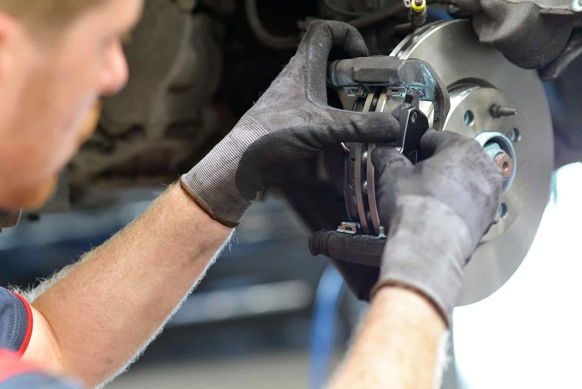 A man is fixing a brake on a car in a garage.