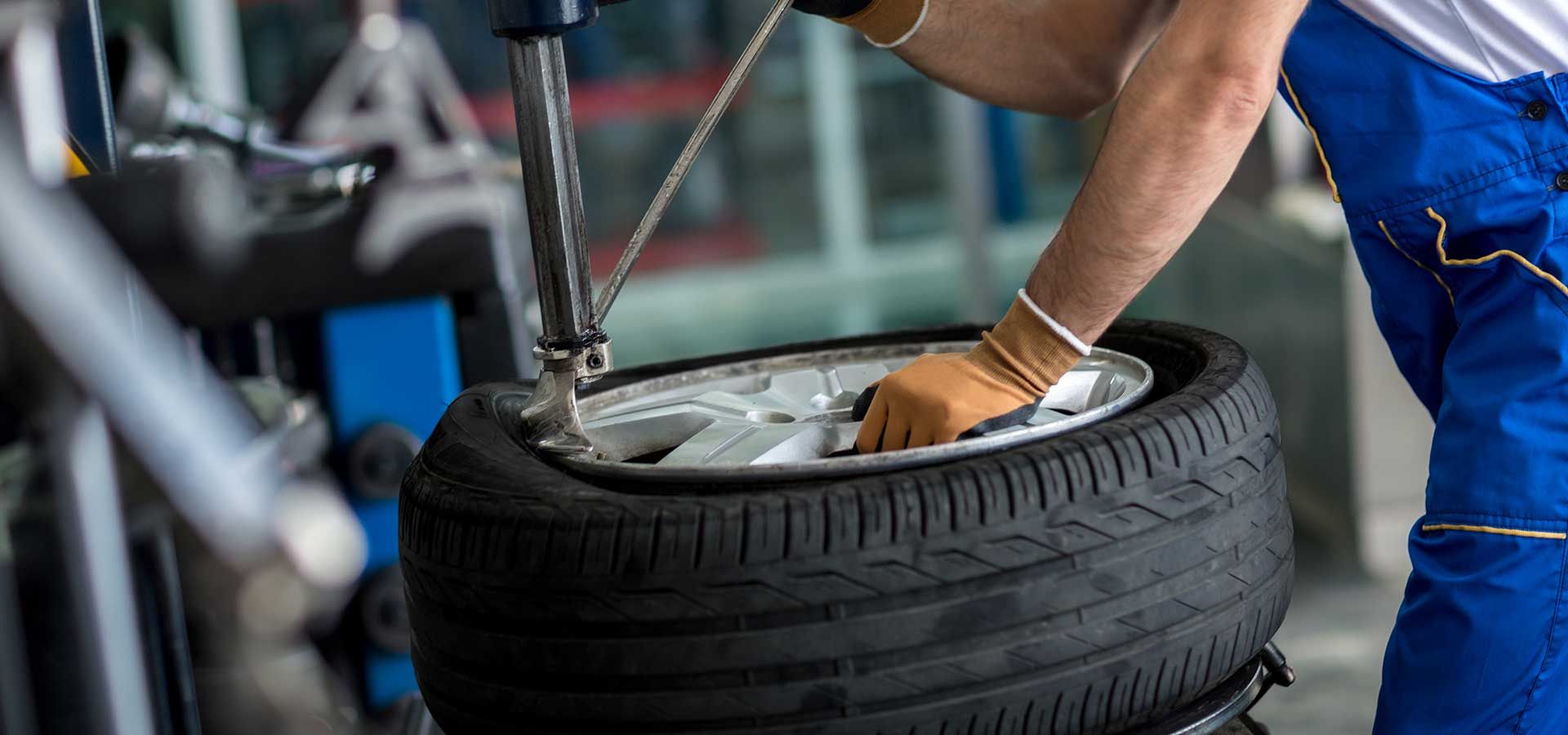 A man is changing a tire on a machine in a garage. | AuotWits