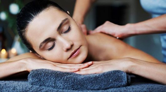 A Woman is Laying on a Table Getting a Massage — Naked Skin Day Spa & Cocktail Lounge in Mooloolaba, QLD