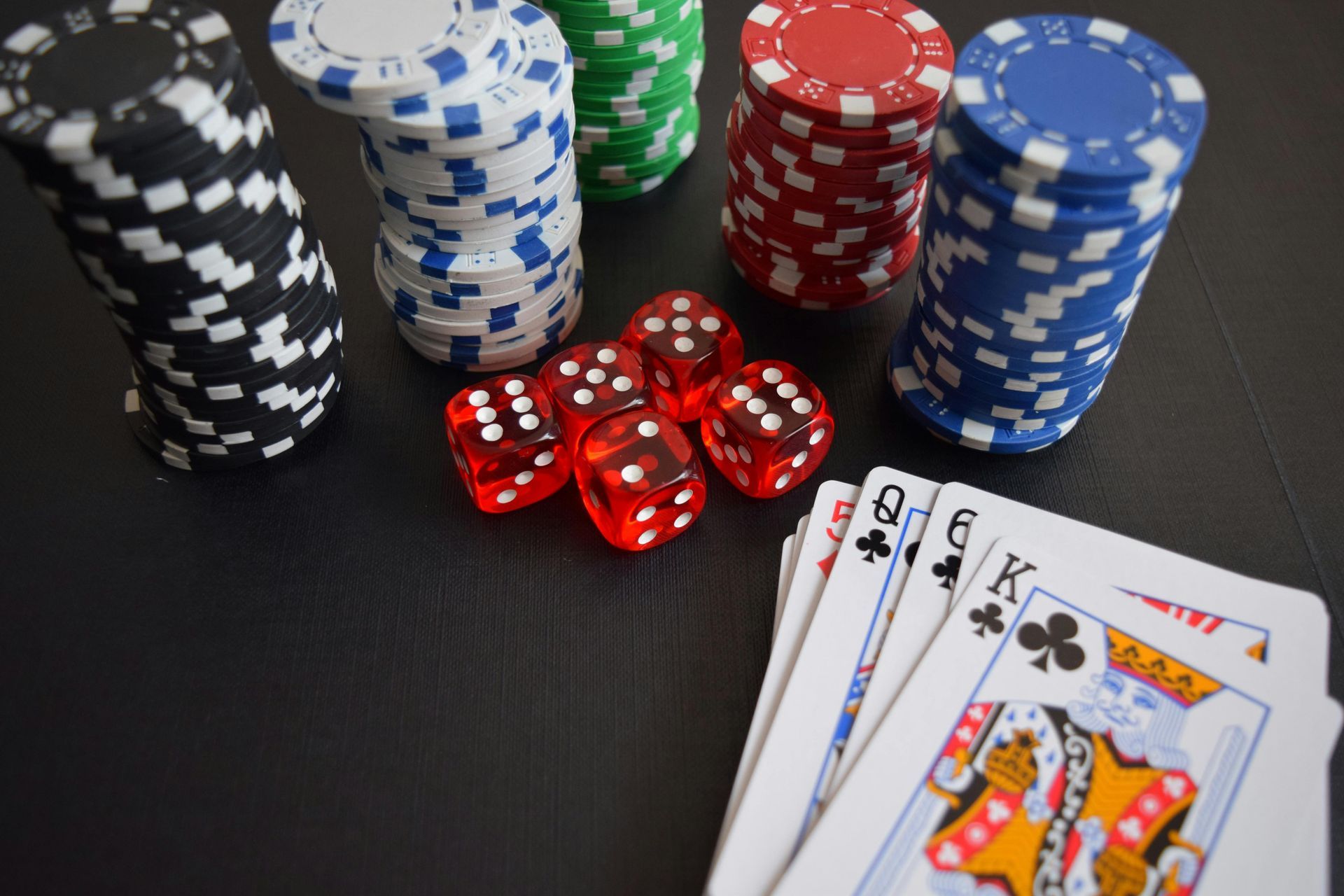 A stack of poker chips , dice , and playing cards on a table.