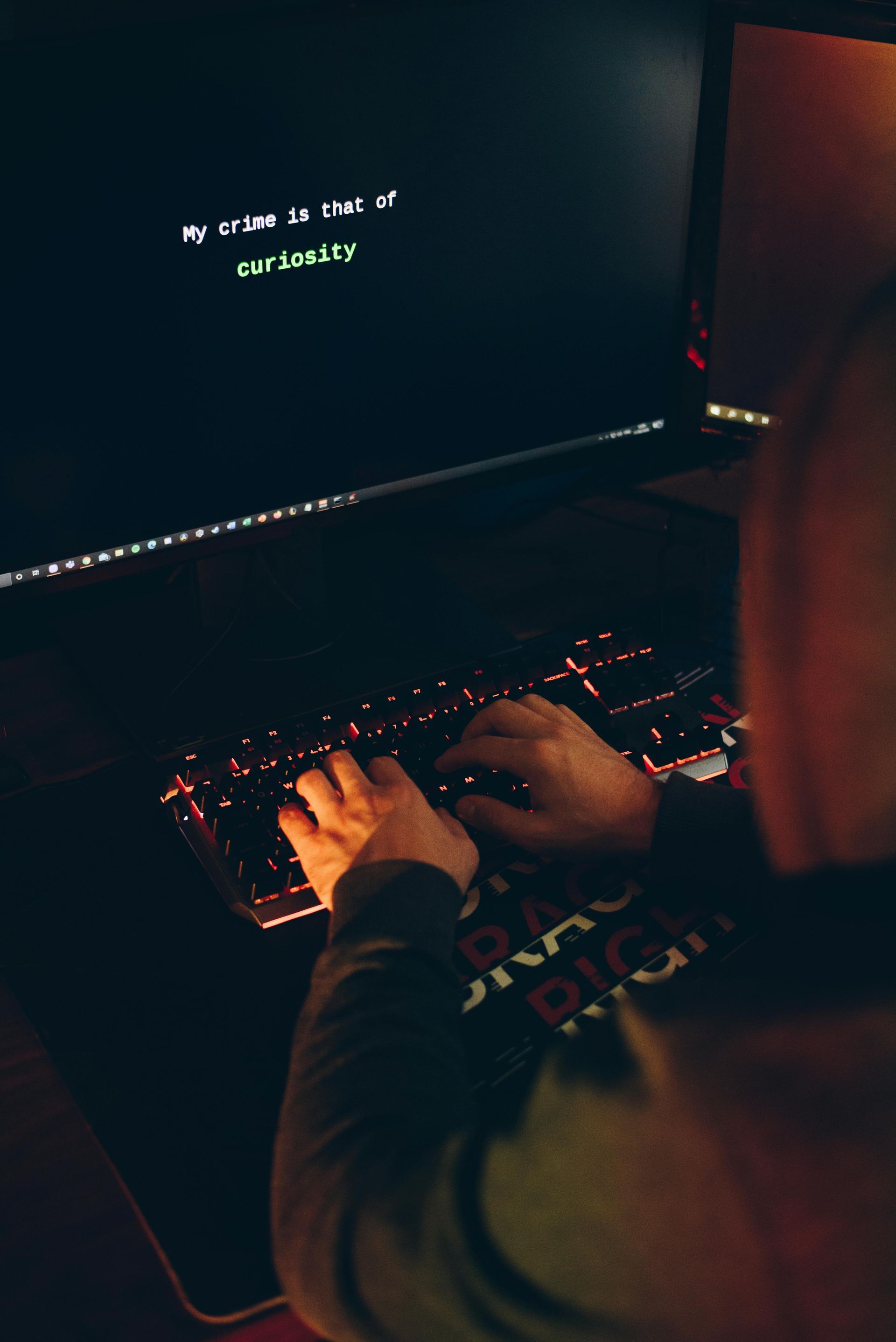 A person is typing on a keyboard in front of a computer monitor.