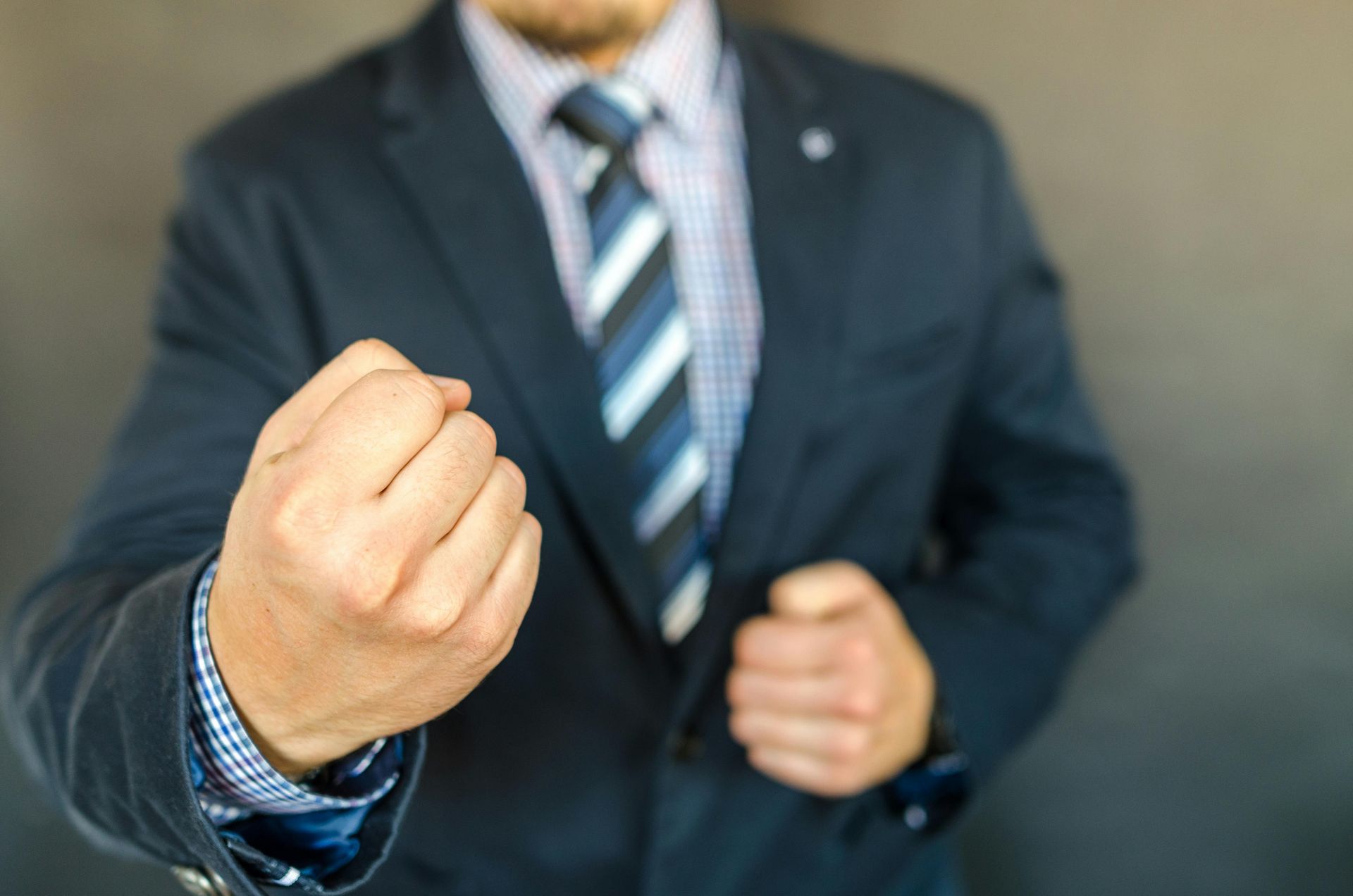 A man in a suit and tie is making a fist.