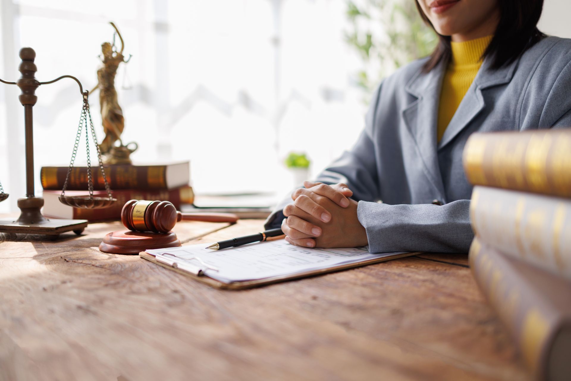 Lawyer’s desk with gavel, scales, Lady Justice, and law books.