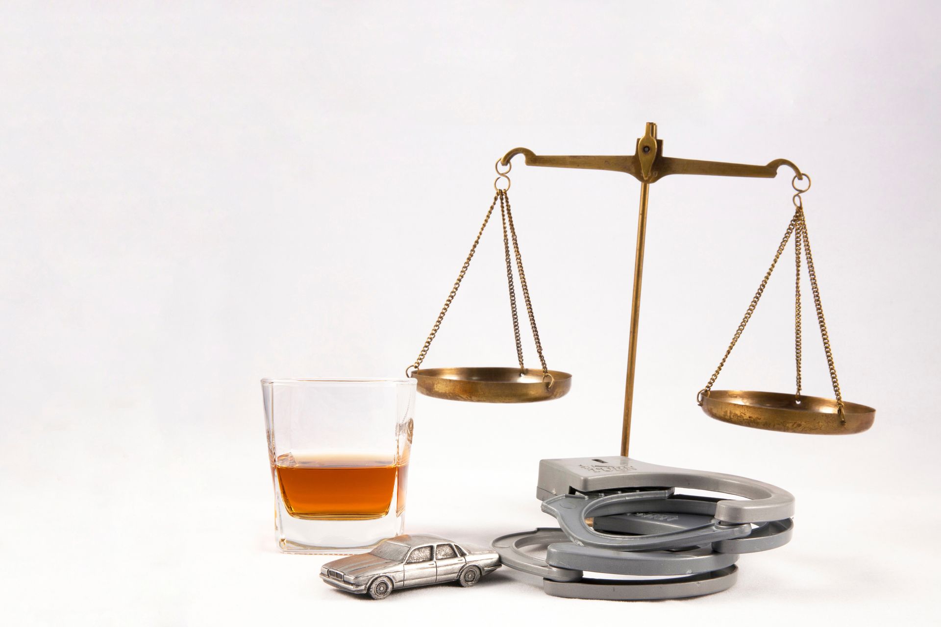 A glass and a pair of handcuffs, next to a pair of golden scales.