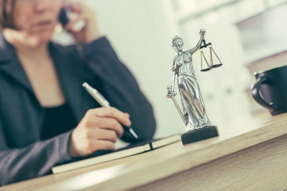 Woman at desk with statue of scales of justice