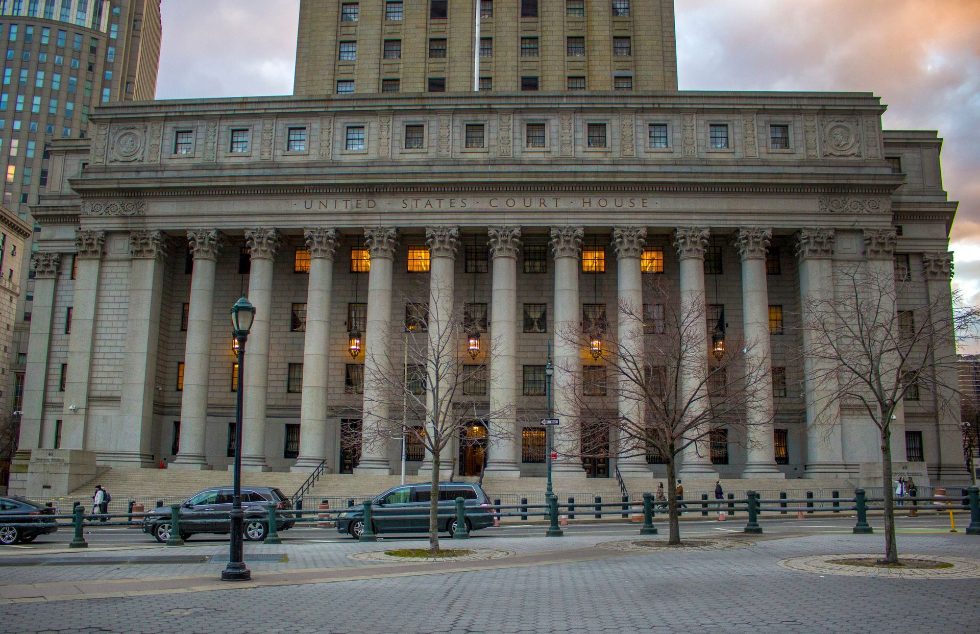 A Large Building with Columns and Cars Parked in Front of It.