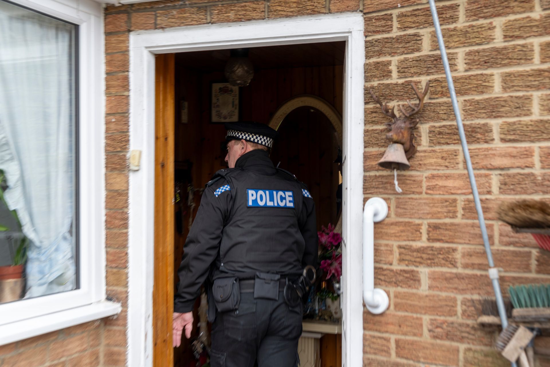 A police officer is standing in the doorway of a house.