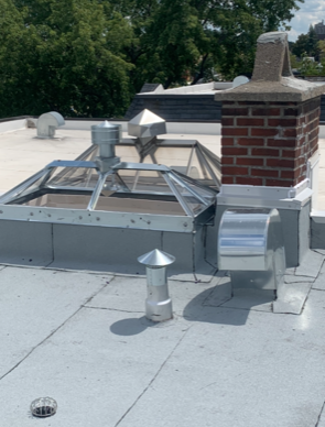 Un toit avec une cheminée en brique et un puits de lumière