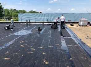 Un groupe de personnes travaille sur un toit à côté d'un plan d'eau.
